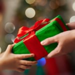 Zu sehen sind zwei Hände und die Übergabe eines Geschenks